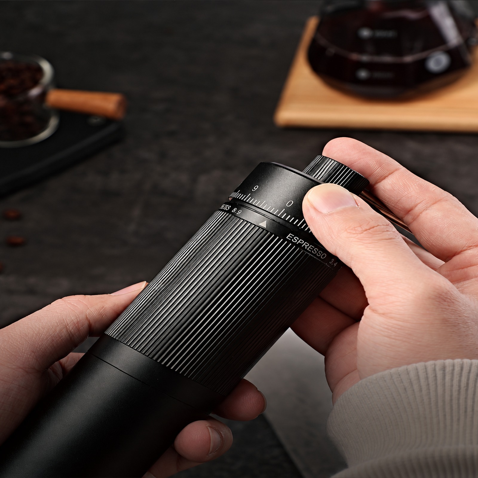 Hands adjusting the dial of the black hand grinder